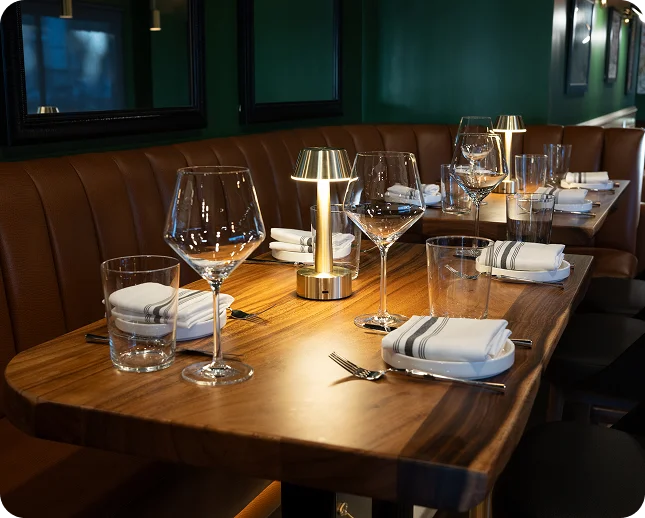 Table set with wine glasses and a brass lamp beside a leather banquette at Prose Kitchen & Bar, a Woodland Hills restaurant